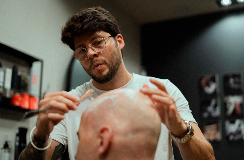 Clark performing a head shave service with a straight razor on a client